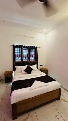 a bedroom with a large bed with black and white pillows at Dolmens Valley Retreat in Marayur in Marayoor