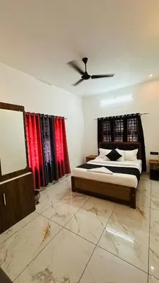 a bedroom with a large bed with red curtains at Dolmens Valley Retreat in Marayur in Marayoor