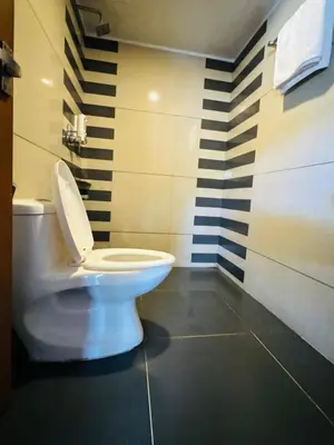 a white toilet in a bathroom with black and white stripes at Kottaram Heritage in Pallipuram