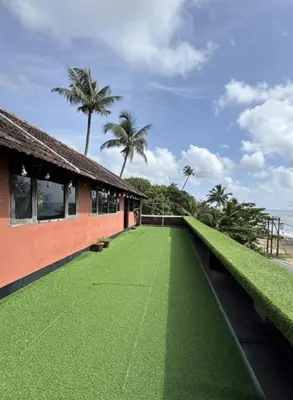 a green roof on a house with palm trees at Kottaram Heritage in Pallipuram