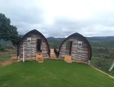 two domesolithicolithic homes on a green field at Bison valley resort Anikorai in Ooty