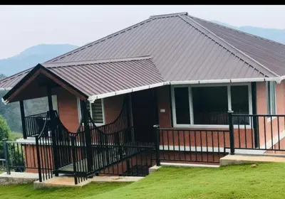 a home with a metal roof and a porch at Bison valley resort Anikorai in Ooty