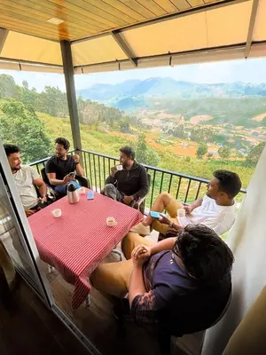 a group of people sitting around a table on a balcony at Bison valley resort Anikorai in Ooty