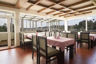 a dining room with tables and chairs and windows at FabHotel Sholas Residency I - Nr Government Rose Garden in Ooty