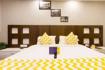 a bedroom with a large bed with yellow and white pillows at FabHotel Sholas Residency I - Nr Government Rose Garden in Ooty