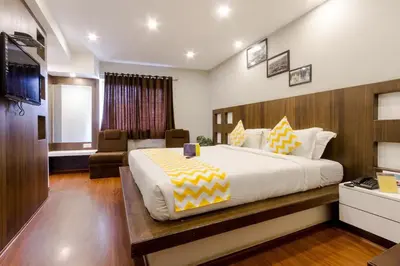 a bedroom with a large bed and a living room at FabHotel Sholas Residency I - Nr Government Rose Garden in Ooty