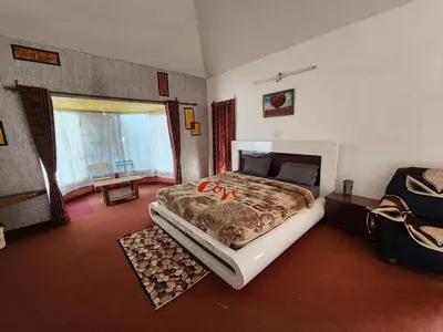 a bedroom with a large bed and a window at Wings Cottage in Ooty