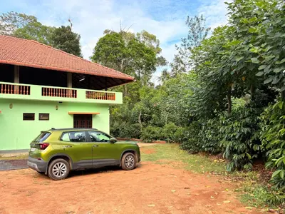 a green car parked in front of a house at KOORGI RETREAT- Coorg in Napoklu