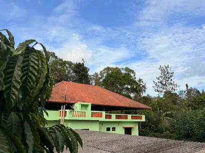 a green building with a red roof at KOORGI RETREAT- Coorg in Napoklu