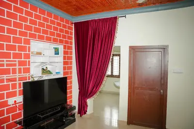a living room with a red curtain and a television at Dua farms in Sultan Bathery