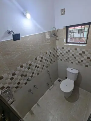 a bathroom with a toilet and a shower with a window at Sankeerthanam - Lounge in serenity in Ernakulam