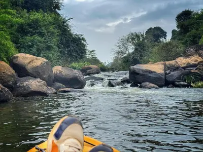 a person is in a kayak on a river at Rafters Retreat Coorg - The Riverside Homestay in Srimangala