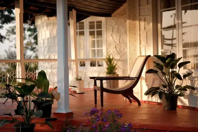a porch with a bench and potted plants and windows at The Hundred House by Kisah Stays in Ambalavayal