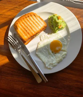 a plate of food with egg and corn and toast at The Hundred House by Kisah Stays in Ambalavayal