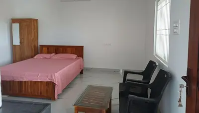 a bedroom with a bed and a black chair at AR Homes in Coimbatore