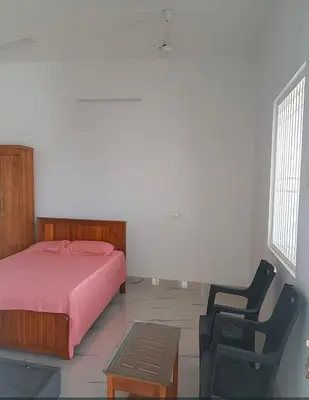 a bedroom with a bed and a chair and a table at AR Homes in Coimbatore