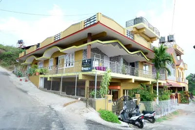 a yellow building with a scooter parked in front of it at Coorg Holiday Homes in Madikeri