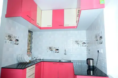 a kitchen with red cabinets and black counter tops at Coorg Holiday Homes in Madikeri