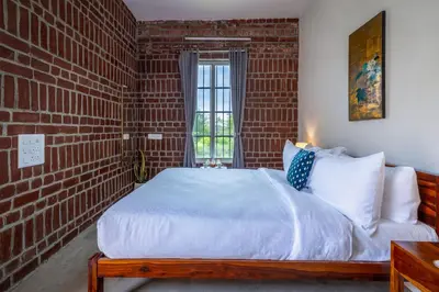 a bedroom with a brick wall and a bed at amã Stays & Trails - Highland Breeze , Coimbatore in Coimbatore