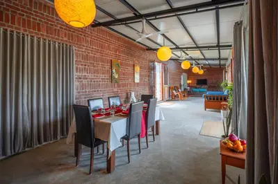 a dining room with a table and chairs and a brick wall at amã Stays & Trails - Highland Breeze , Coimbatore in Coimbatore