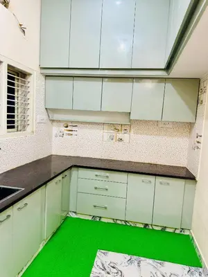 a kitchen with white cabinets and a green floor at Flats in city center, next to NEXUS MALL in Mysore