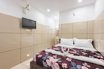a bedroom with a bed and a tv on the wall at Oxe residency in Kozhikode