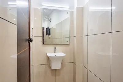 a white bathroom with a sink and a mirror at Oxe residency in Kozhikode