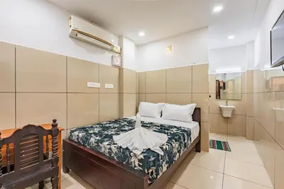 a small bedroom with a bed and a toilet at Oxe residency in Kozhikode