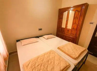a small bedroom with a bed and a wooden cabinet at Villa 9 degrees north in Sultan Bathery