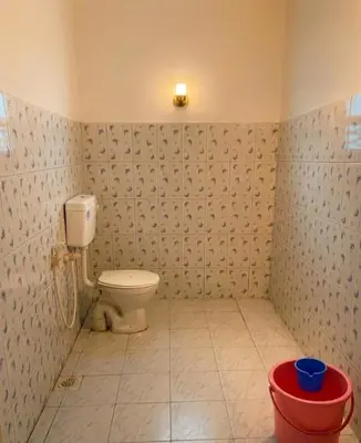 a bathroom with a toilet and a red bucket at Villa 9 degrees north in Sultan Bathery