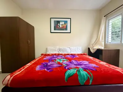 a bed with a red blanket with flowers on it at NILGIRIS Inn in Kotagiri