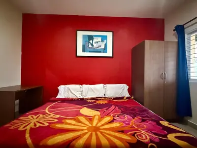 a bedroom with a red wall and a bed at NILGIRIS Inn in Kotagiri