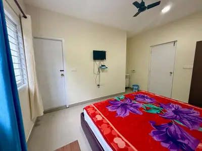 a bedroom with a red bed with flowers on it at NILGIRIS Inn in Kotagiri