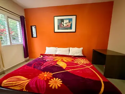 a bedroom with a bed with an orange wall at NILGIRIS Inn in Kotagiri