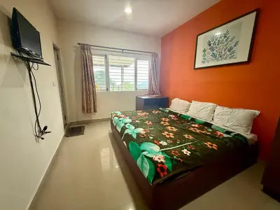 a bedroom with a bed with an orange wall at NILGIRIS Inn in Kotagiri