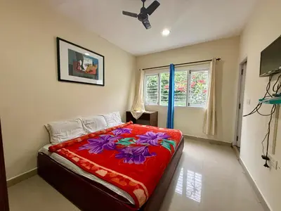 a bedroom with a bed with a red blanket at NILGIRIS Inn in Kotagiri
