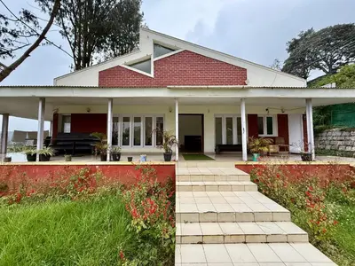 a red and white house with a porch at NILGIRIS Inn in Kotagiri