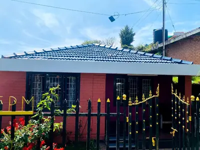 a red house with a white roof and a fence at Skyline Haven cottage in Ooty
