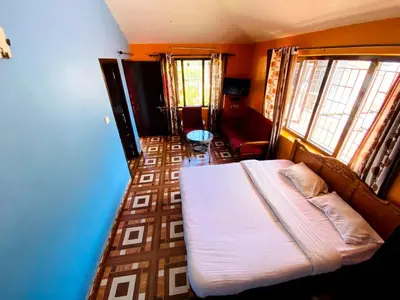 a bedroom with a bed and a couch and windows at Skyline Haven cottage in Ooty