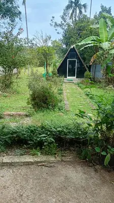 a small black building with a door in a field at Manna Homestay coorg in Kushālnagar