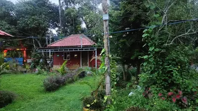 a red house with a red roof in a yard at Manna Homestay coorg in Kushālnagar