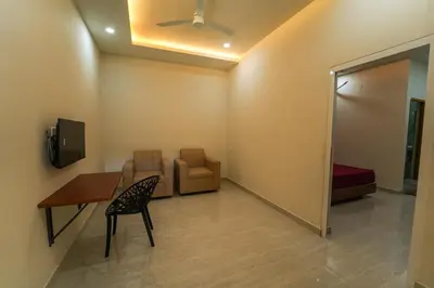 a waiting room with a table and a chair and a tv at SK Premium Residency in Edakkara
