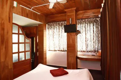 a bedroom with a bed and a window with curtains at Rainbow Homestay Wayanad in Kalpetta
