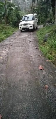 a white vehicle parked on a dirt road at Morning mist holidays Thusharagiri in Vallikavungal