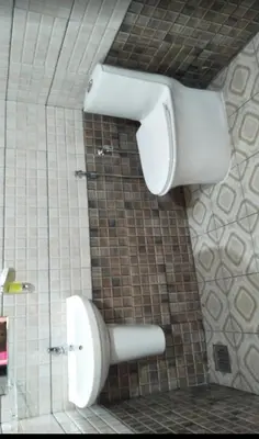 a white toilet in a bathroom with a tiled wall at Morning mist holidays Thusharagiri in Vallikavungal
