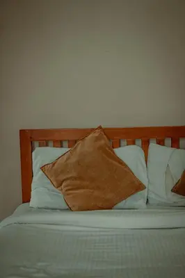a bed with white pillows and a wooden headboard at Fine Homes in Kalpetta