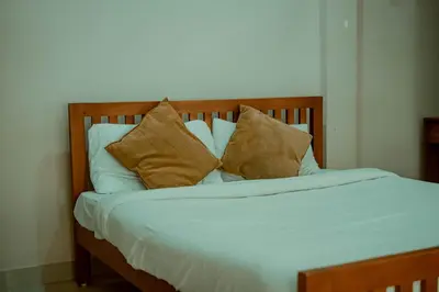 a bed with white sheets and brown pillows at Fine Homes in Kalpetta