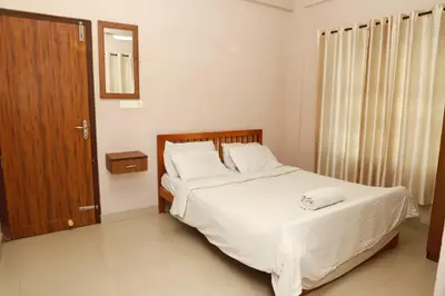 a bedroom with a bed and a wooden door at Fine Homes in Kalpetta