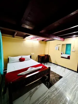 a bedroom with a bed with a red blanket and a table at Edwin and Edrin Service Villa in Wayanad