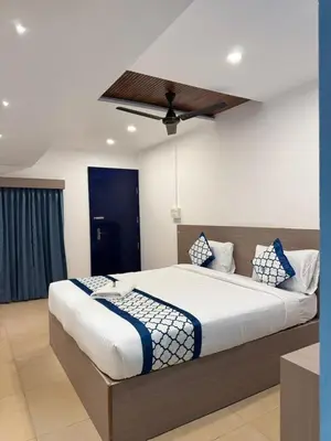 a bedroom with a large bed with blue and white pillows at Kadale Boutique Beach Stay in Kannur